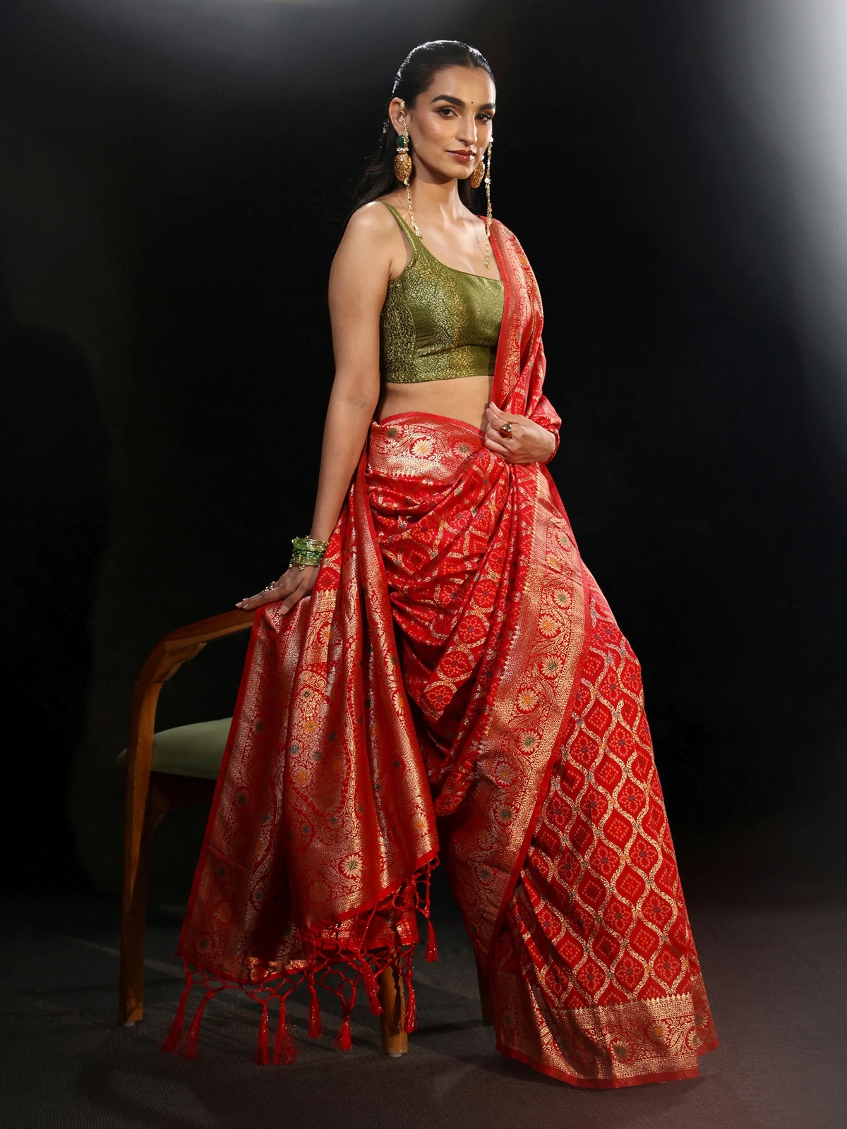 Model draped in a vermilion red gharchola silk saree with gold zari checks